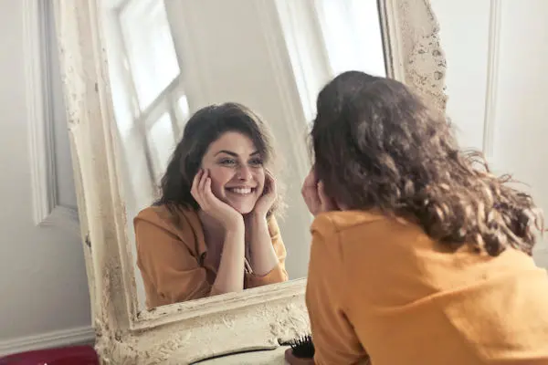 woman smiling into mirror